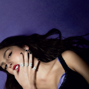 Olivia Rodrigo lays against a purple background for the cover art of her second album, GUTS. / Larissa Hoffman