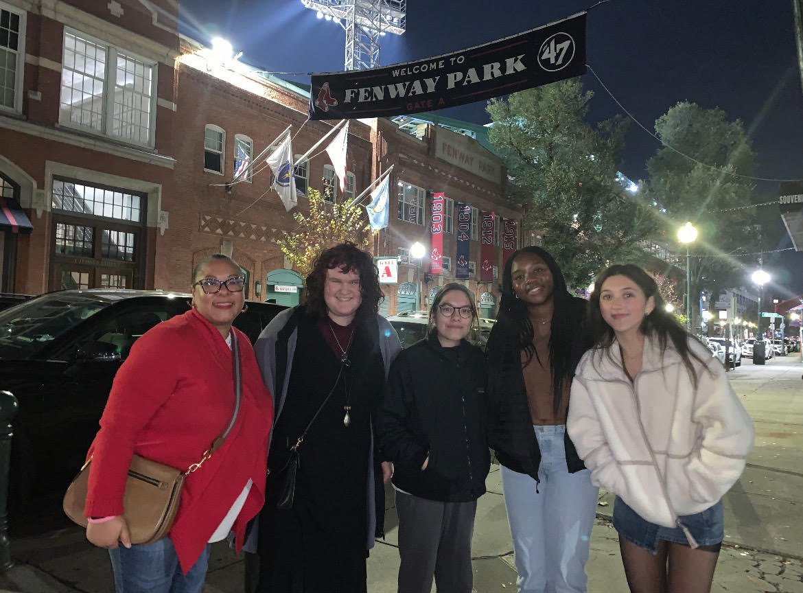 From left to right: Kamilah Lawson, Rozalia Finkelstein, Ermila Mazariegos, Zoe Sermons, and Julia Gwin pose in front of the Fenway Park banner. 