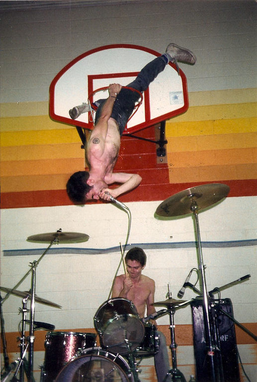 Guy Piccioto of Fugazi climbs through a basketball hoop at a local DIY show, 1988