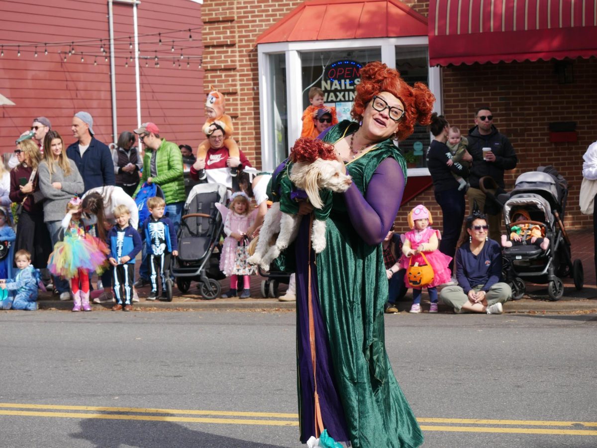 A patron dressed at Winfred Sanderson from Hocus Pocus, a classic 90s Halloween movie, holding her dog in a matching costume.