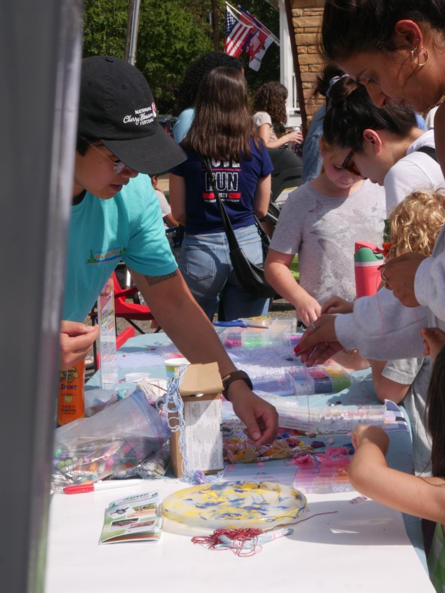 Members of the Wilderness Kids Organization craft bracelets with the community. 