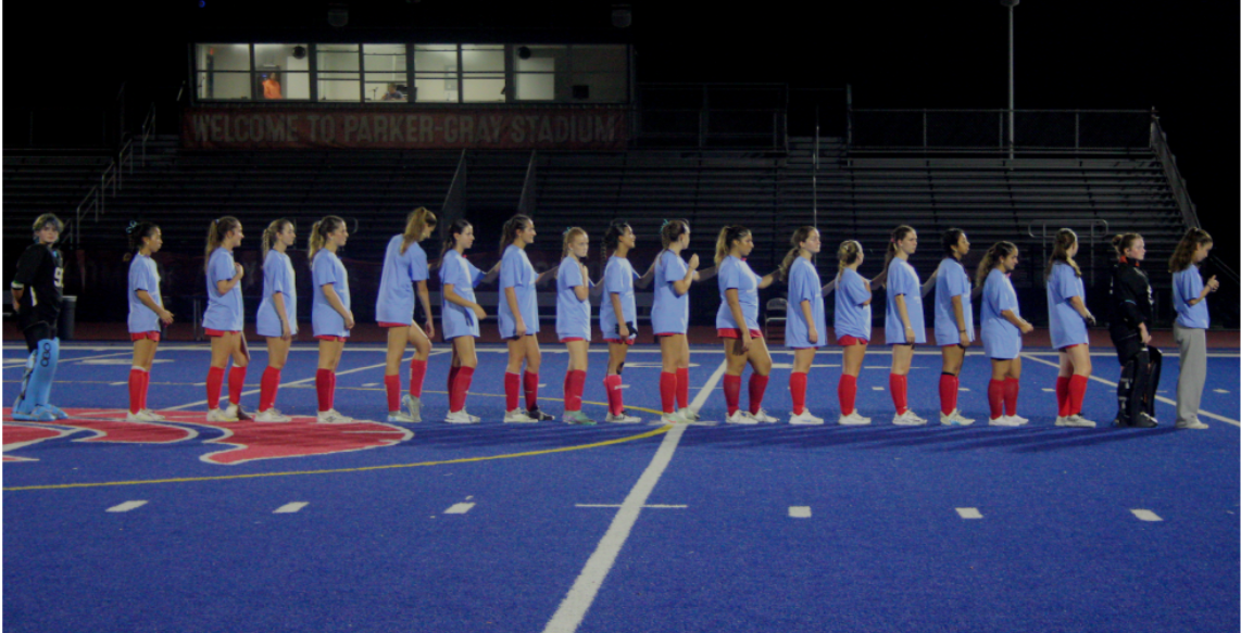 The ACHS field hockey team lines up before the game for the pledge of allegiance. 