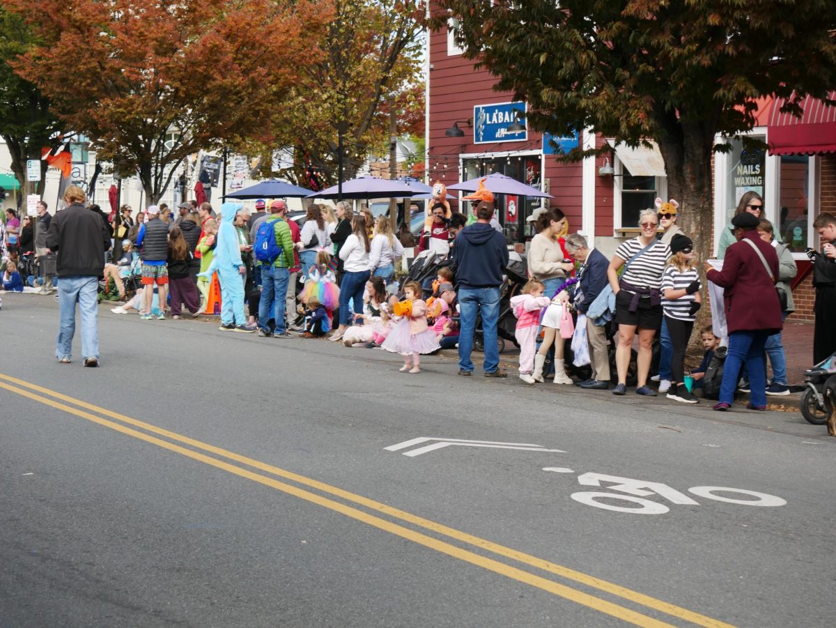 Community members sit at the side of the road to watch the parade.