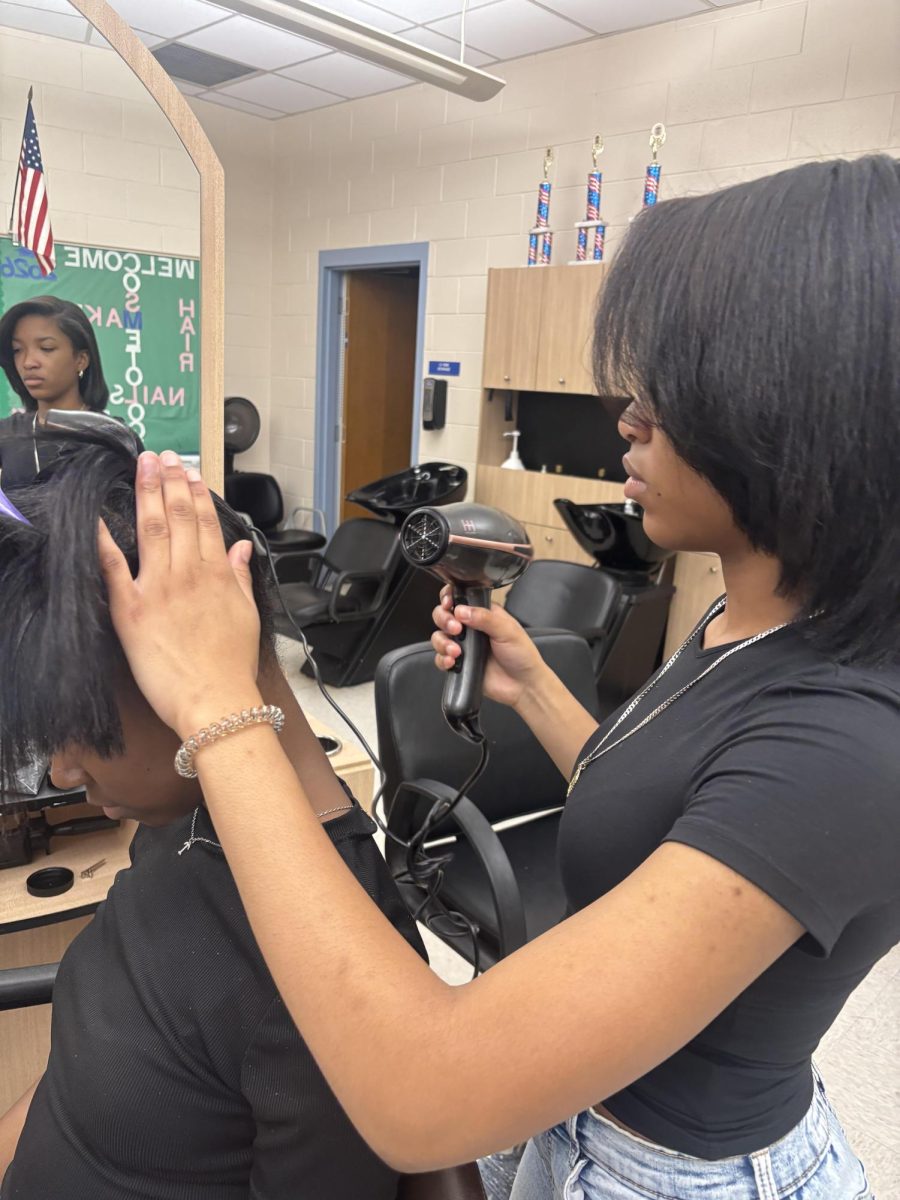 Angel Martin styles a client's hair in the ACHS cosmetology classroom.