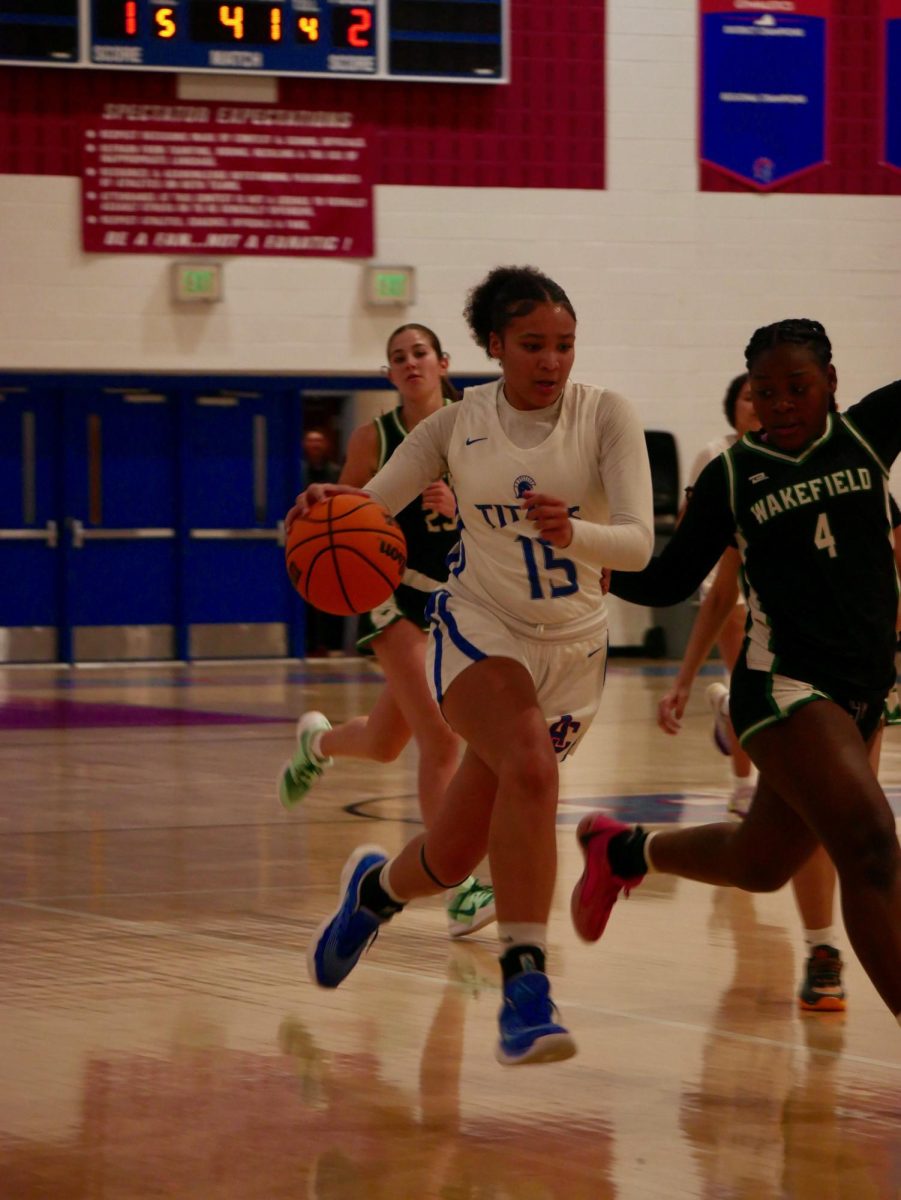 Sophomore Gabrielle Barnes-Thomas dribbles the basketball down the court, in pursuit by a Wakefield defender.
