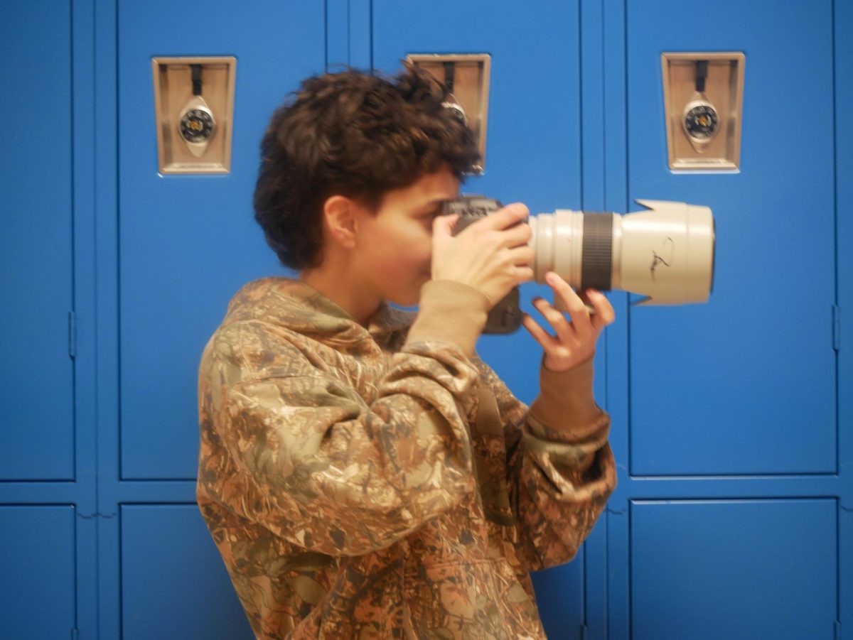 Kayden Molina, who runs photography business MolinaLens, snaps photos in front of ACHS lockers.