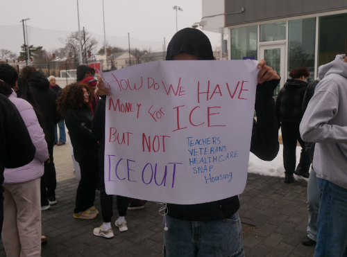 An anonymous student outside of the Minnie Howard campus holds a sign with the writing “How do we have money for ICE but not teachers, veterans, health care, snap, housing. ICE OUT”  / Carly Edmonson for Theogony
