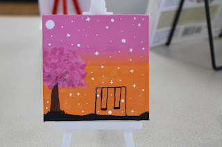 "Where Blossoms Meet the Sunrise" features a swing set under the evening sky, accompanied by a blossoming tree. The anonymous painter describes "A lovely view to watch during sunrise."
